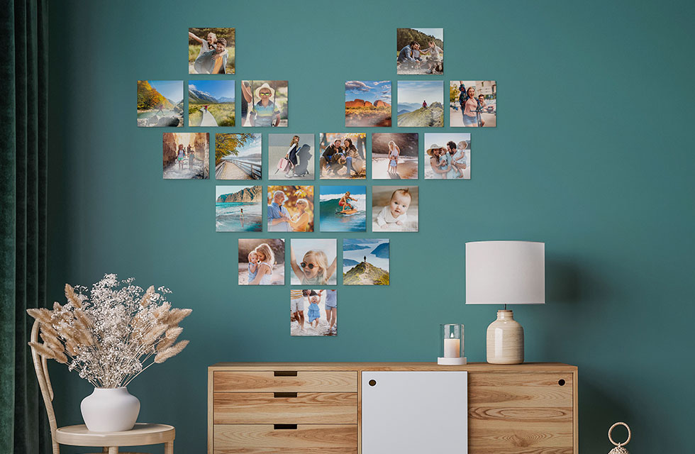 Multiple Snapfish Photo Tiles are displayed in the shape of a heart on a green wall above a dresser with a lamp on top