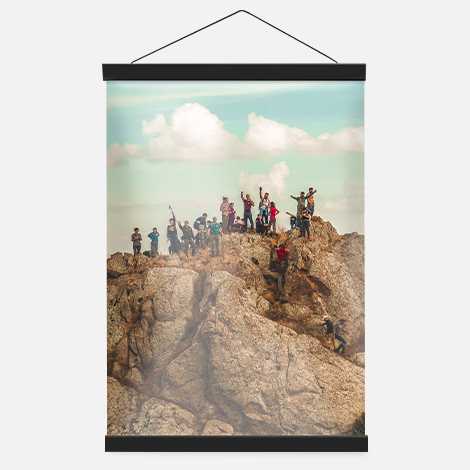 Hanging photo poster showing a group of tourists on top of a rocky landscape. 