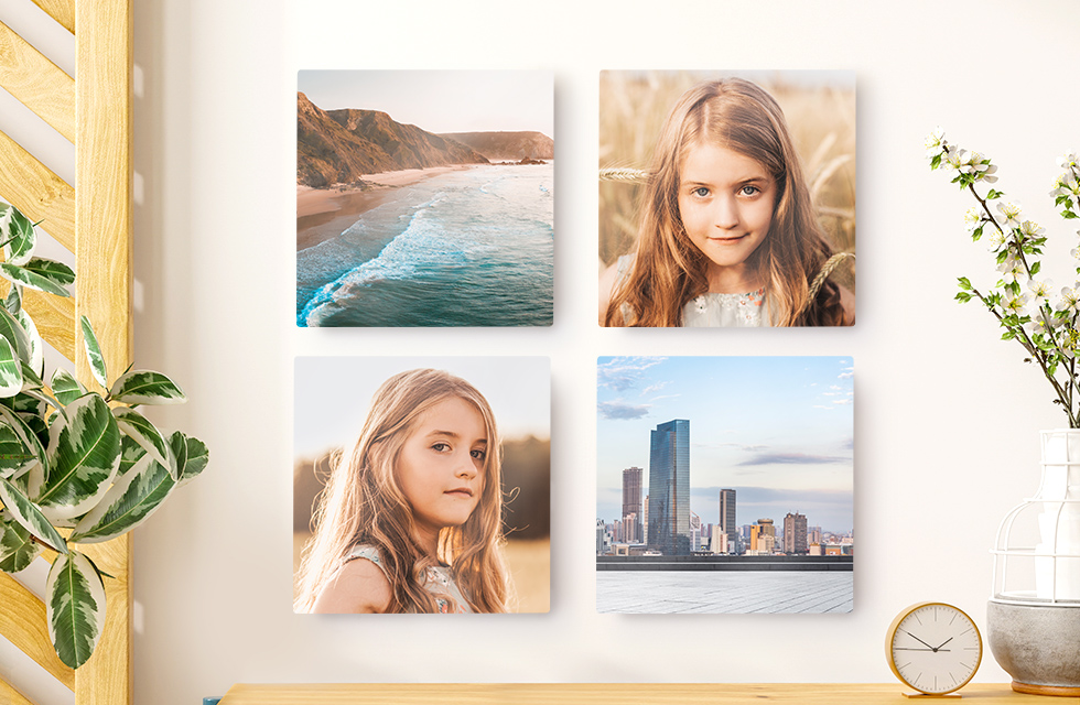 A set of four Snapfish Photo Tiles featuring family and vacation photos is displayed on a wall with a hat and plant nearby