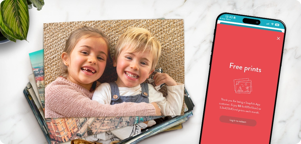 Stack of prints showing and phone showing snapfish free prints